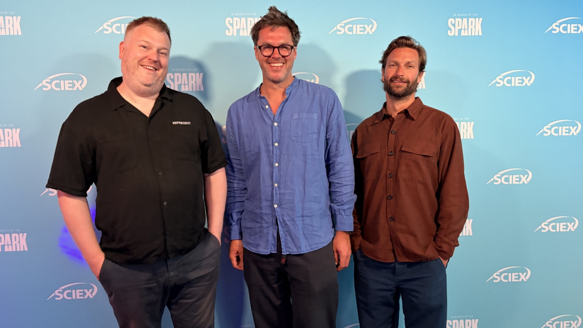 Three men standing on a red carpet against a backdrop that reads "SCIEX" and "In search of the spark"